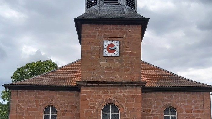 Rotes Backsteingebäude mit einem Turm und Rundbogenfenstern.