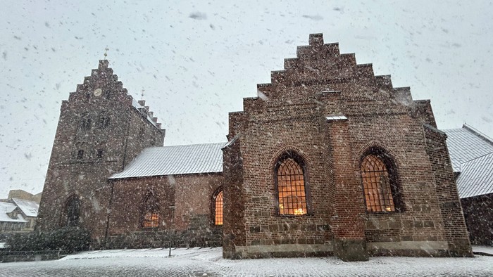 Gamle kirke i snefaldende landskab