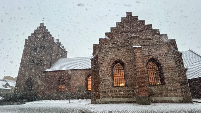 Gamle kirke i snefaldende landskab