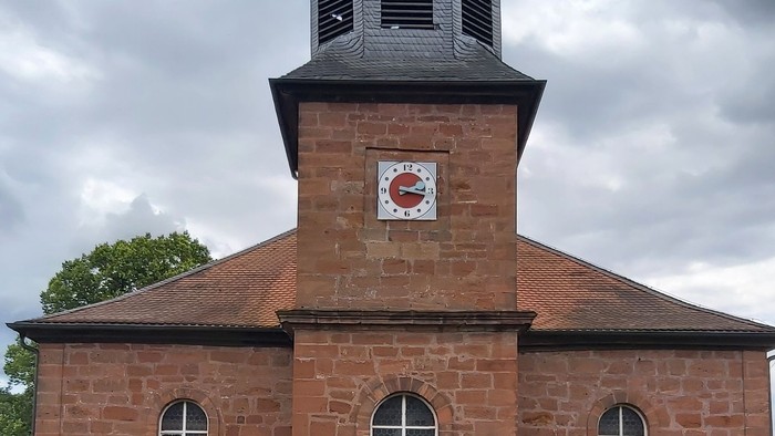 Rotes Backsteingebäude mit einem Turm und Rundbogenfenstern.
