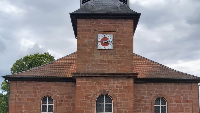 Rotes Backsteingebäude mit einem Turm und Rundbogenfenstern.