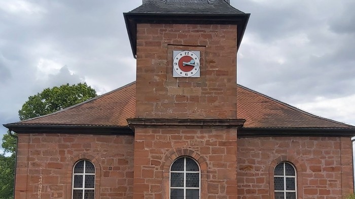 Rotes Backsteingebäude mit einem Turm und Rundbogenfenstern.