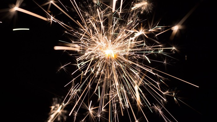 En fyrværkeriudbrudder med gule og hvide spær i mørke himmel.