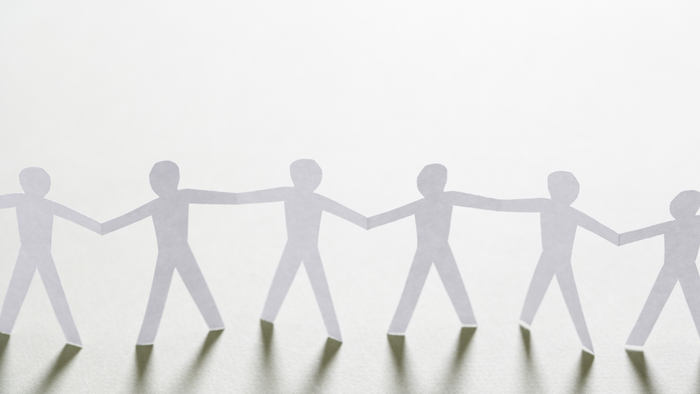 Eine Reihe von Papierfiguren hält sich an den Händen