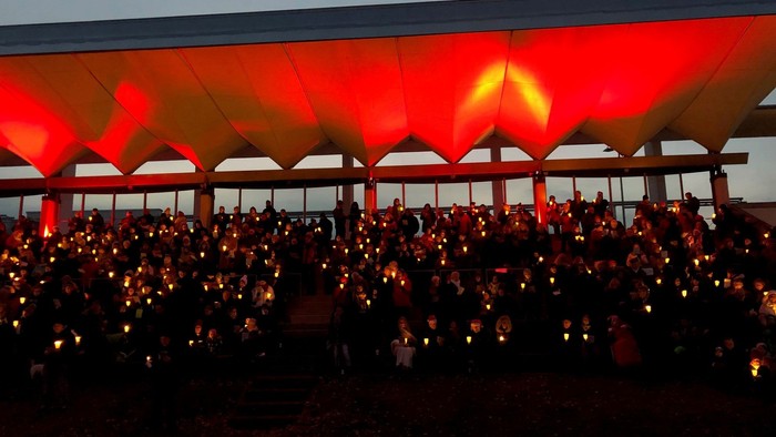 Große Menschenmenge bei Nachtveranstaltung unter rot beleuchtetem Zelt