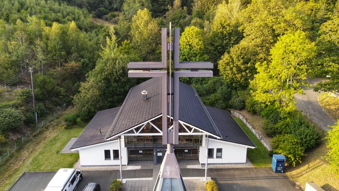 Kirchengelände mit großem Kreuz und Parkplatz