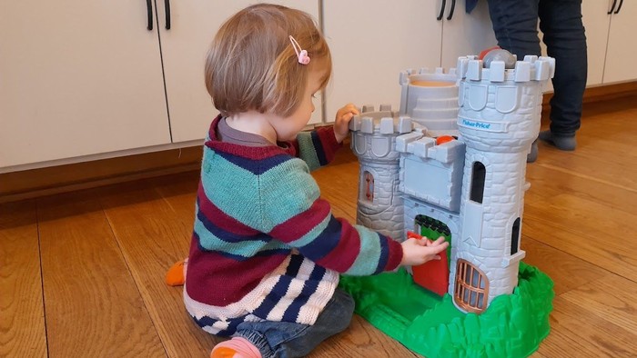 Børn spiller med legetøjs slot på gulv.
