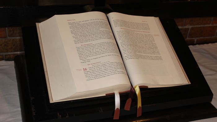 Offene Bibel auf schwarzem Ständer