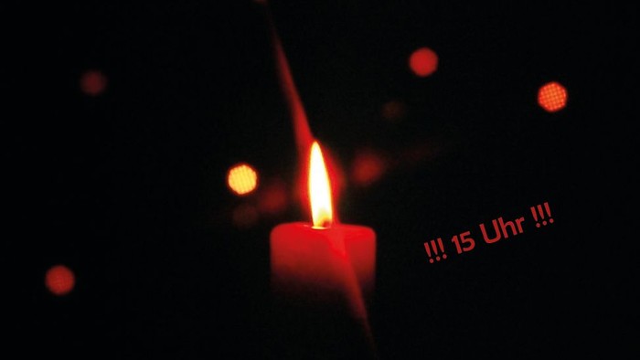 Ein rote Kerze leuchtet vor dunklem Hintergrund, Text 15 Uhr