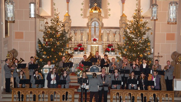 Ein Chor singt in einer Kirche vor zwei Weihnachtsbäumen