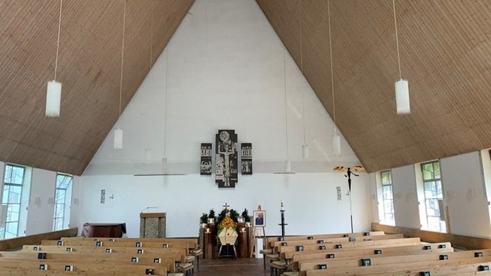 Leere Kirche mit Holzpaneelen und Kreuz an der Wand