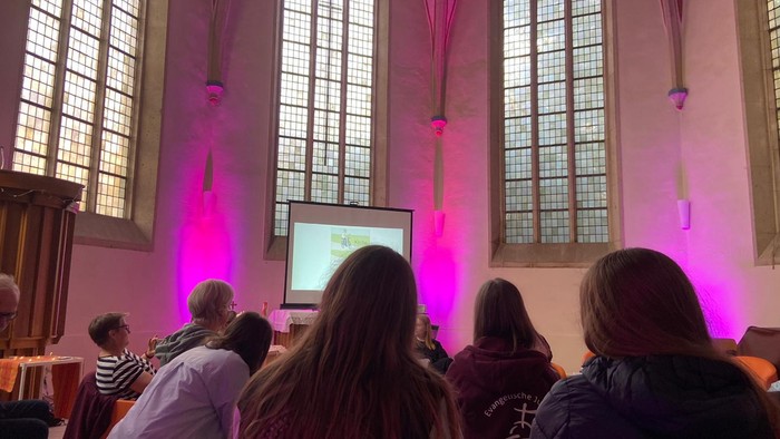Personen schauen sich in einer Kirche einen Videoprojektor an