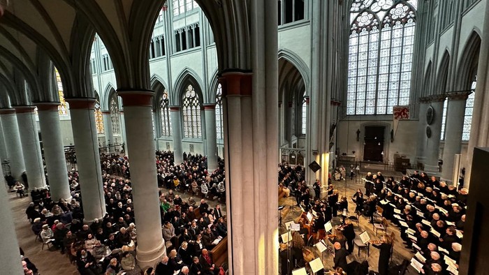 Große Kirchenhalle mit vielen Menschen und hohen Bögen