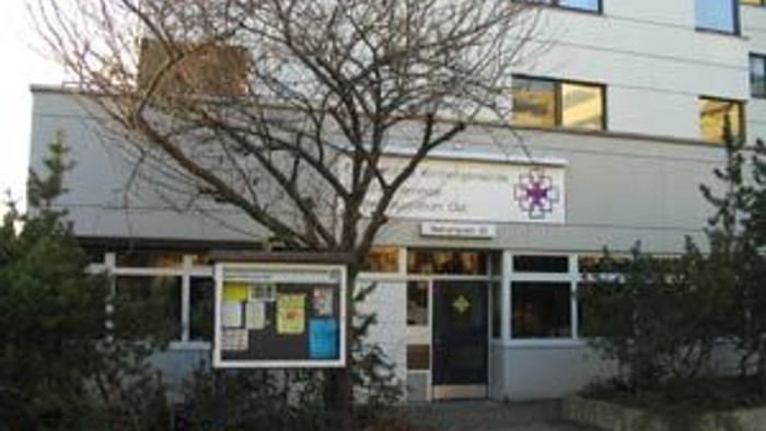 Das Bild zeigt ein Gebäude mit einem Baum und einem Schild.