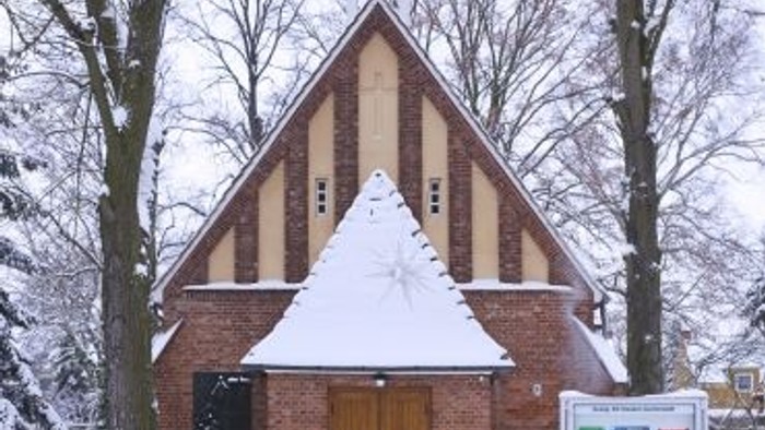 Weiße Kirche im Winter mit hohem Turm und Schnee auf Dach