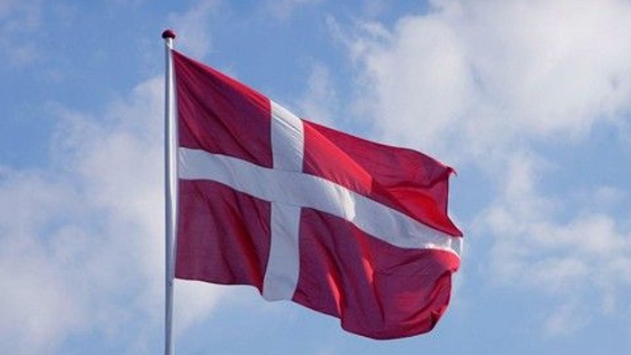 Et dansk flag, der vajer mod en delvist skyet blå himmel.