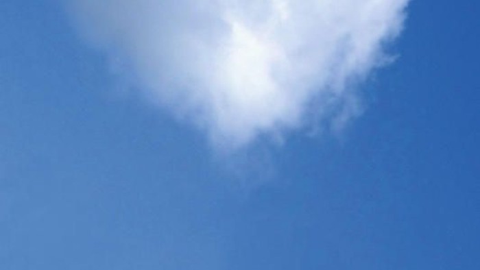 Eine herzförmige Wolke am klaren blauen Himmel.