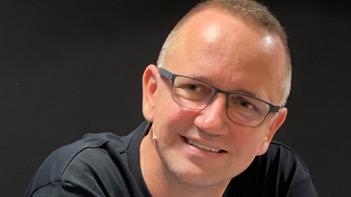 En smilende mand med briller og kort hår.