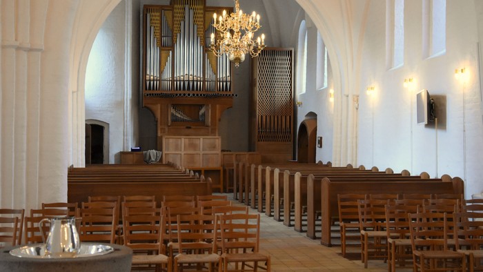 Indenrigspart af kirke med orgel og træbænke.