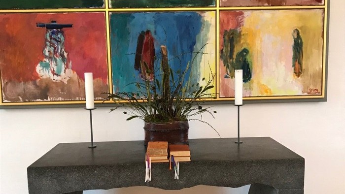 En moderne indretning med sort bord, to lysekøn, og farvede malerier på væggen