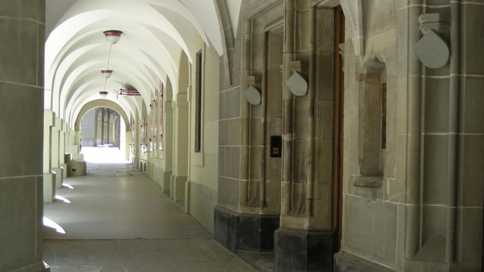 Ein langer, gewölbter Flur mit steinernen Säulen und Türen.