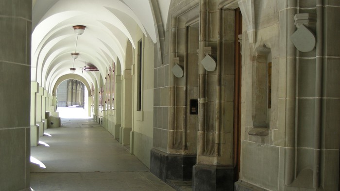 Ein langer, gewölbter Flur mit steinernen Säulen und Türen.