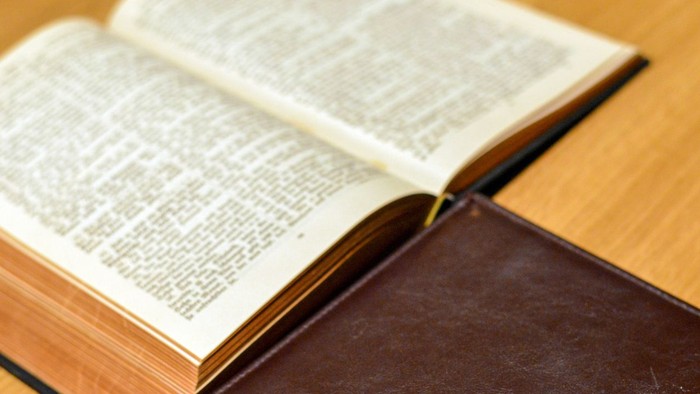 Offenes Buch mit Kreuz auf Einband auf Holzoberfläche