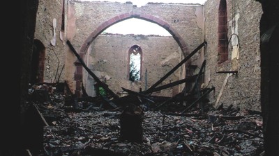 Ein verfallenes, teilweise eingestürztes Gebäudeinneres, übersät mit Schutt und Trümmern.