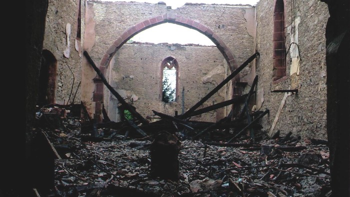 Ein verfallenes, teilweise eingestürztes Gebäudeinneres, übersät mit Schutt und Trümmern.
