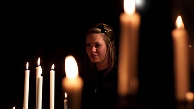 En kvinde med blonder og en blomst i håret står mellem lysende lygter.