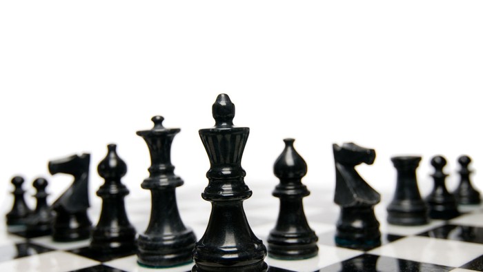 Es ist ein Schachbrett mit schwarzen Spielfiguren zu sehen
