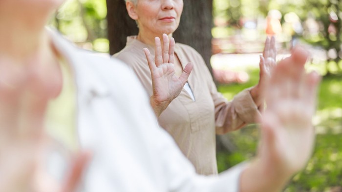 Eine ältere Frau führt Tai Chi im Park aus.