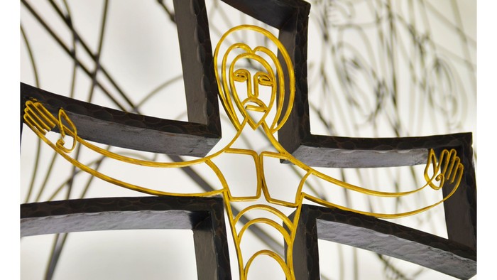 Das Bild zeigt ein goldenes Kreuz mit einer Darstellung von Jesus Christus daran.