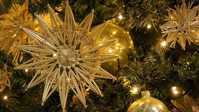 Eleganter Weihnachtsbaum, geschmückt mit goldenen Kugeln, Sternen und funkelnden Lichterketten.