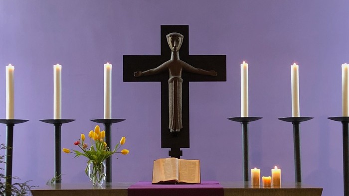 Altar der Weihnachtskirche mit Bibel, Blumen und drei Kerzen geschmückt