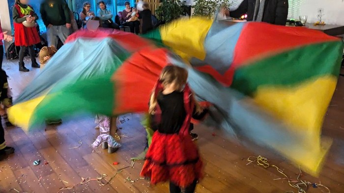 Kinder in Kostüm spieln mit großem bunten Tuch