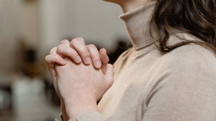 En person med sammenfoldede hænder og en turtagelset trøje.