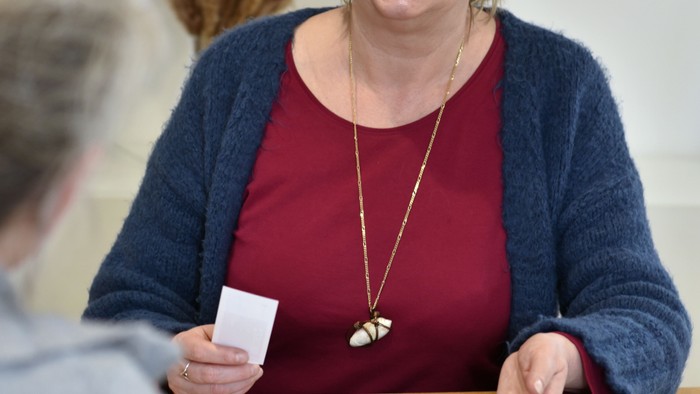 Eine ältere Frau spielt ein Brettspiel und hält eine Spielkarte in der Hand