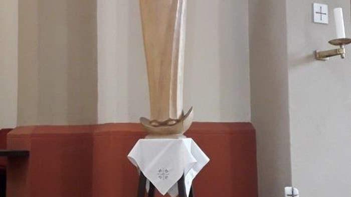 Eine Statue der Jungfrau Maria mit Baby Jesus in einer Kirche, umgeben von Blumen und Kerzen.