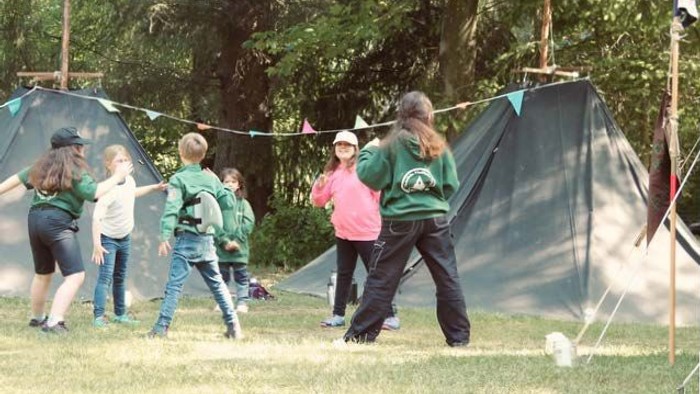 Kinder spielen im Freien vor Zelten
