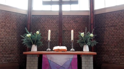 Altar in Kirche mit Kreuz, Kerzen und Blumen