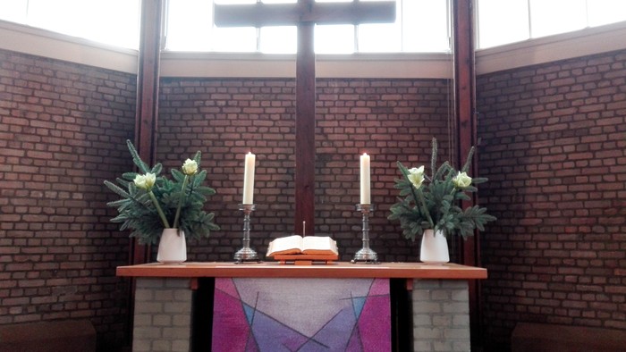 Altar in Kirche mit Kreuz, Kerzen und Blumen