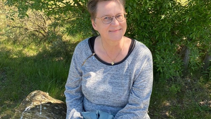 En kvinde sidder på en træstamme i skoven.