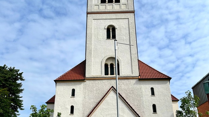 Weiße Kirche mit hohem Glockenturm und rotem Dach.