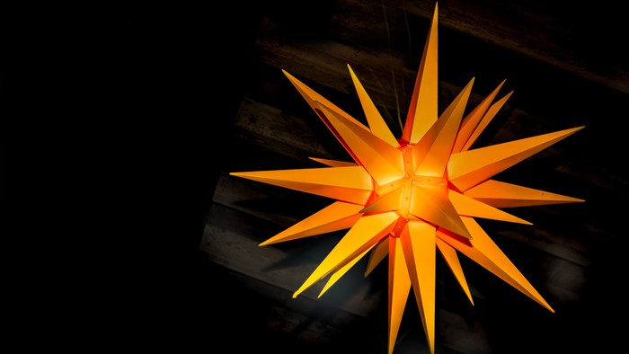 Ein leuchtender orangefarbener Stern hängt im dunklen Himmel.