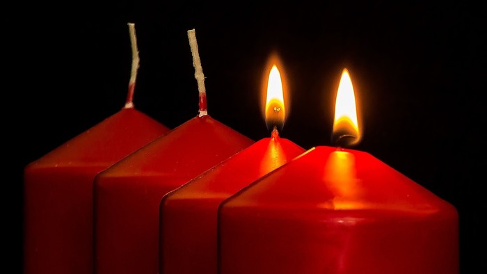 Vier rote Kerzen, drei unangezündet, eine angezündet