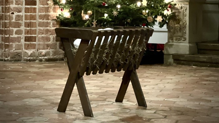 Ein geschmückter Weihnachtsbaum steht in einem Korb auf einem Kopfsteinpflasterhof.