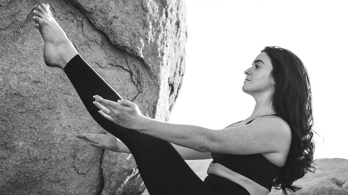 Eine Frau klettert an einer Felswand.