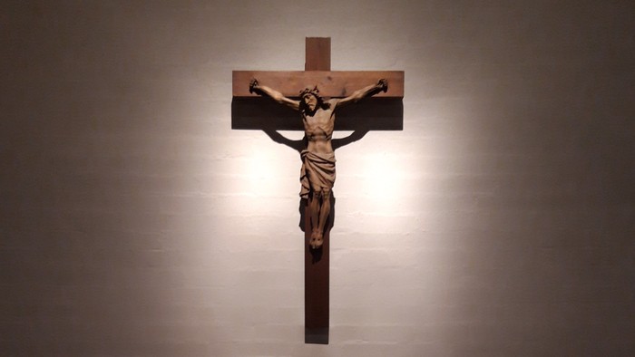 Ein Kruzifix an der Wand über einem Altar mit bunten Punkten