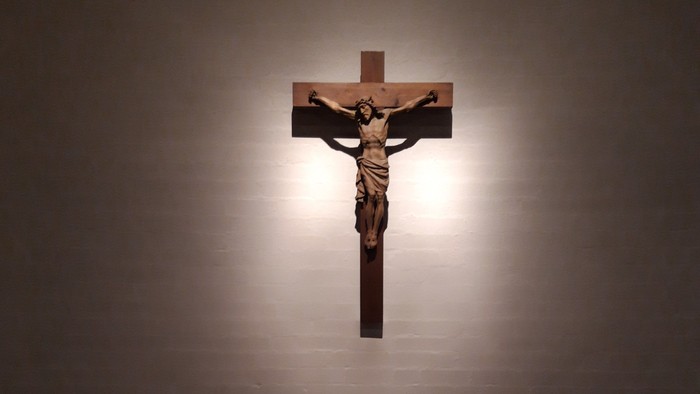 Ein Kruzifix an der Wand über einem Altar mit bunten Punkten